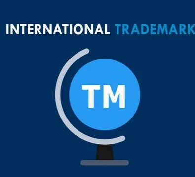 An graphic illustration on a dark blue background featuring the words "INTERNATIONAL TRADEMARK" in white and light blue sans-serif font. Below the text is a stylized blue globe with the white letters "TM" in the center, supported by a grey minimalist stand.